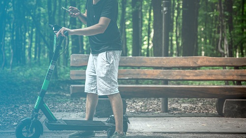 mężczyzna w parku jadacy hulajnoga elektryczna